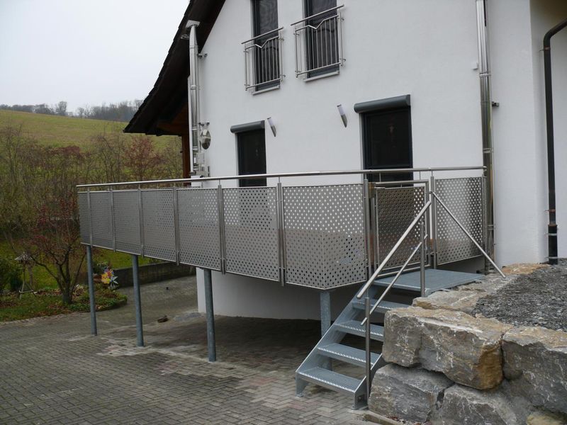Balkongeländer aus Edelstahl-Lochblech und verzinkte Außentreppe an einem Wohnhaus