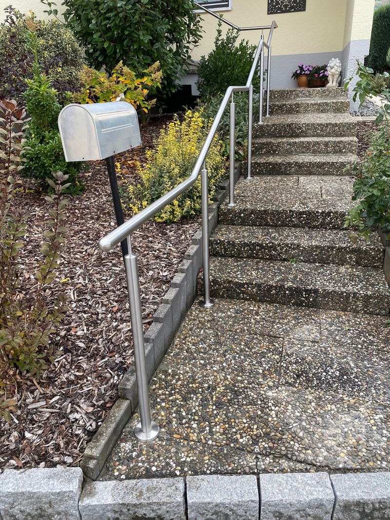Handlauf aus Edelstahlrohr an einem Treppenaufgang mit Natursteinstufen