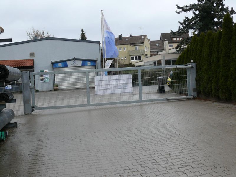Einflügeliges verzinktes Drehtor mit Antrieb und Doppelstabmatten-Füllung an einer Firmeneinfahrt